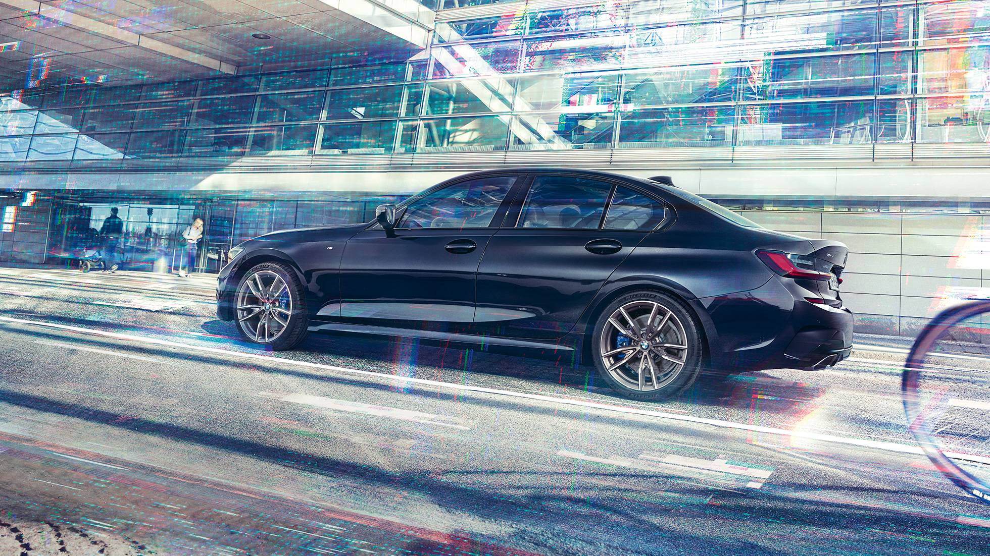 Side view of the BMW M340i xDrive in front of an urban building.