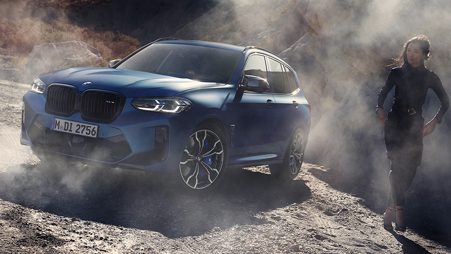 BMW X3 M Competition F97 LCI Facelift 2021 Frozen Marina Bay Blue metallic three-quarter front view standing in stony terrain with female model